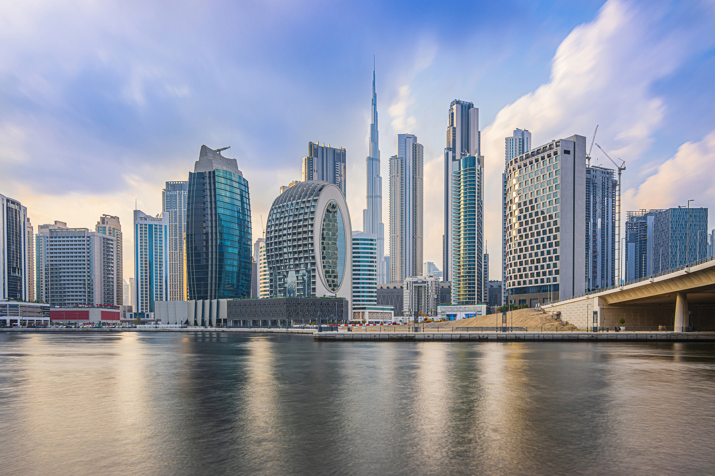 Dubai with skyscrapers and Burj Khalifa in the evening. Skyline with a cloudy sky in the evening mood. Waterfront in Dubai Harbour. Houses with glass front and concrete facades architecture