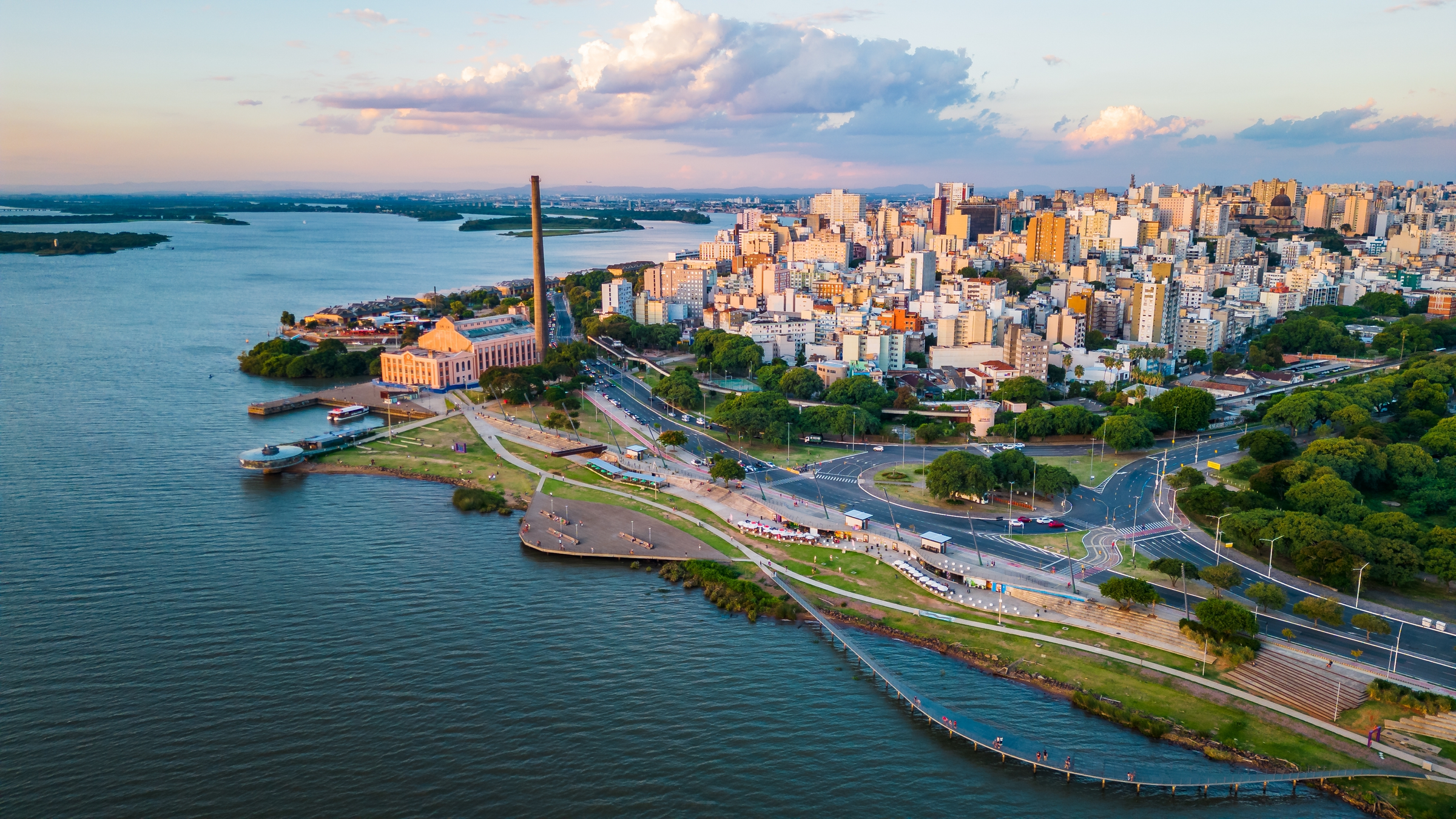 Aerial Drone Fly Above Beautiful Cityscape of Porto Alegre Brazil Neighborhood Gasometro, Guaiba Lake, Architecture and Road Traffic with Warm Skyline