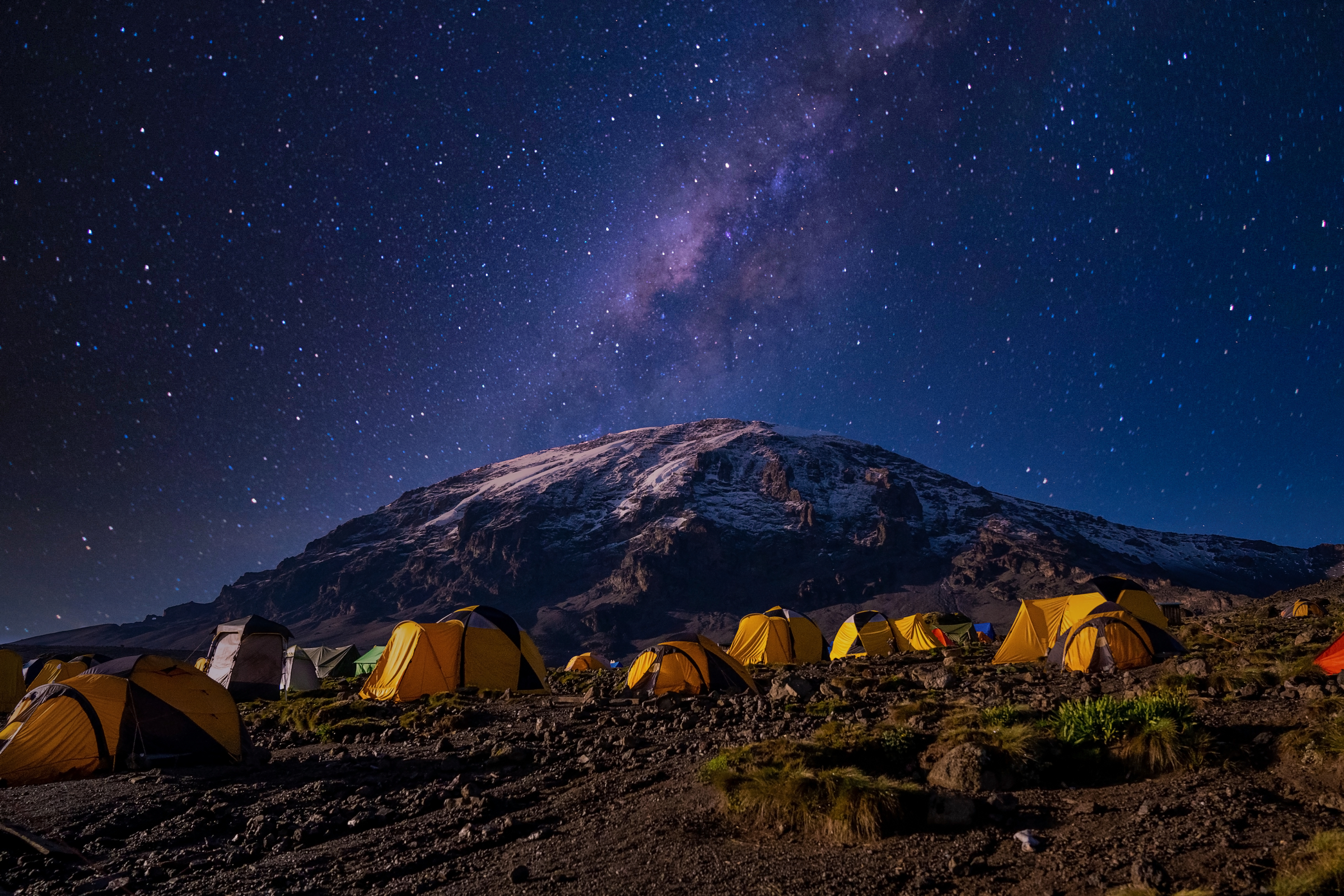 Beautiful view of the milky way over mount Kilimanjaro, Tanzania with many tents at the base camp. Millions of stars in the night African sky.