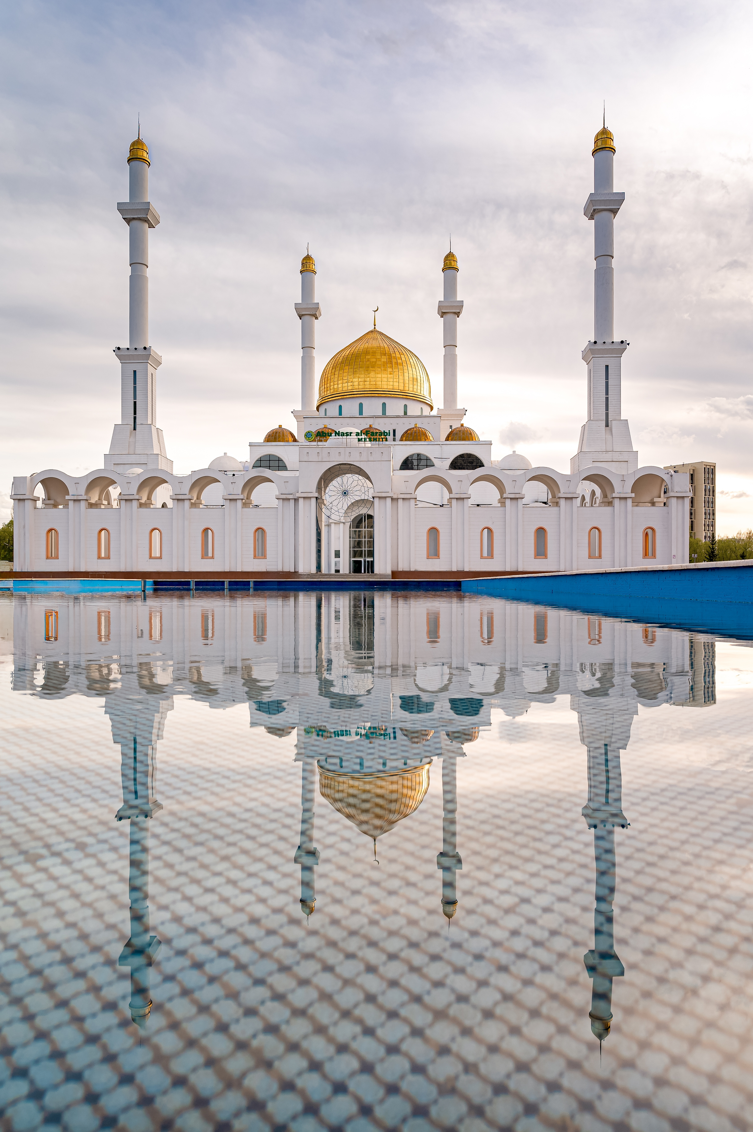 White mosque with gold dome reflected in nearby water in Astana, Kazakstan