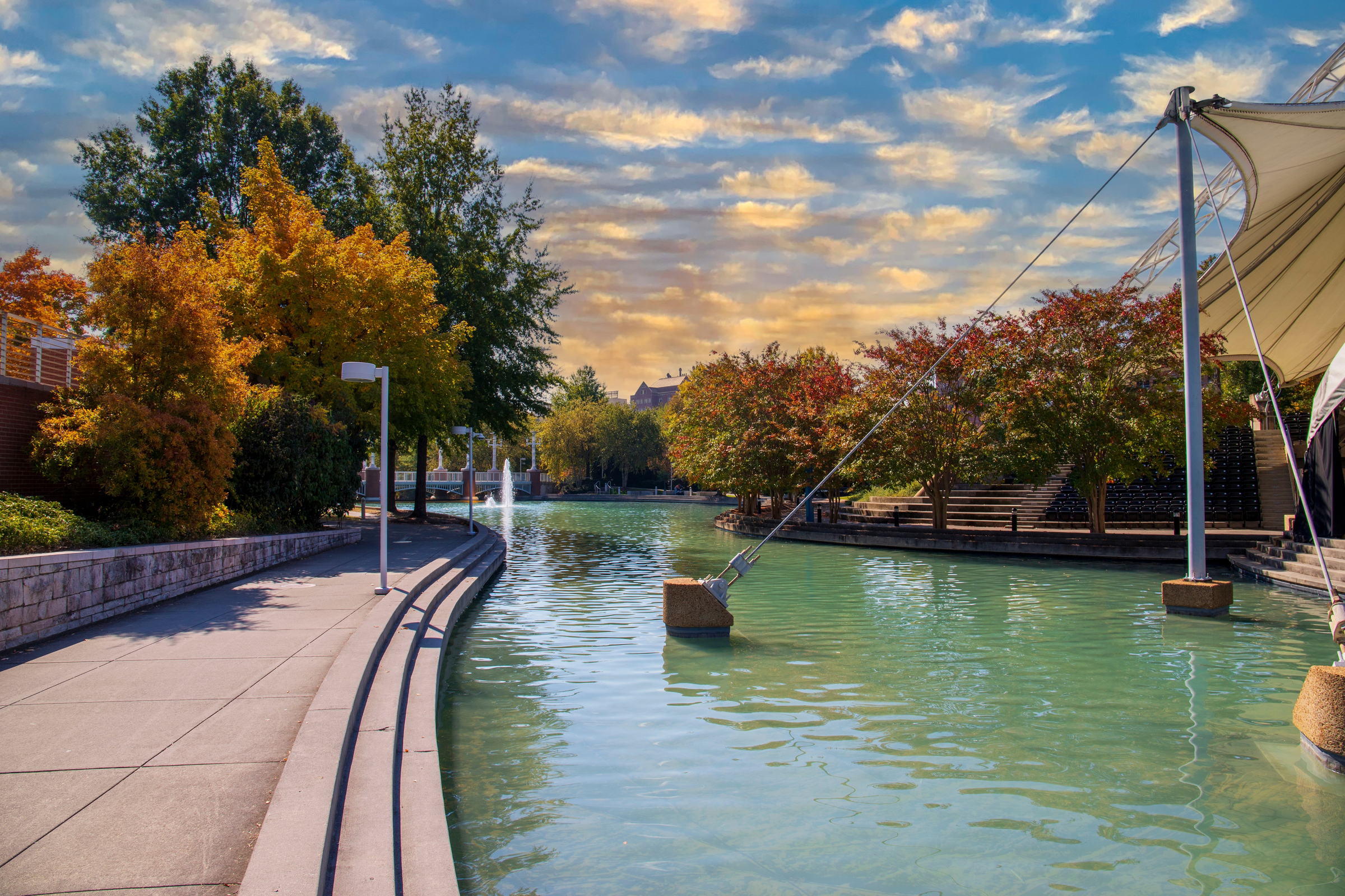 a stunning autumn landscape at World's Fair Park with a pool with blue water surrounded by red and yellow autumn trees and lush green trees and plants with a gorgeous blue sky in Knoxville Tennessee	