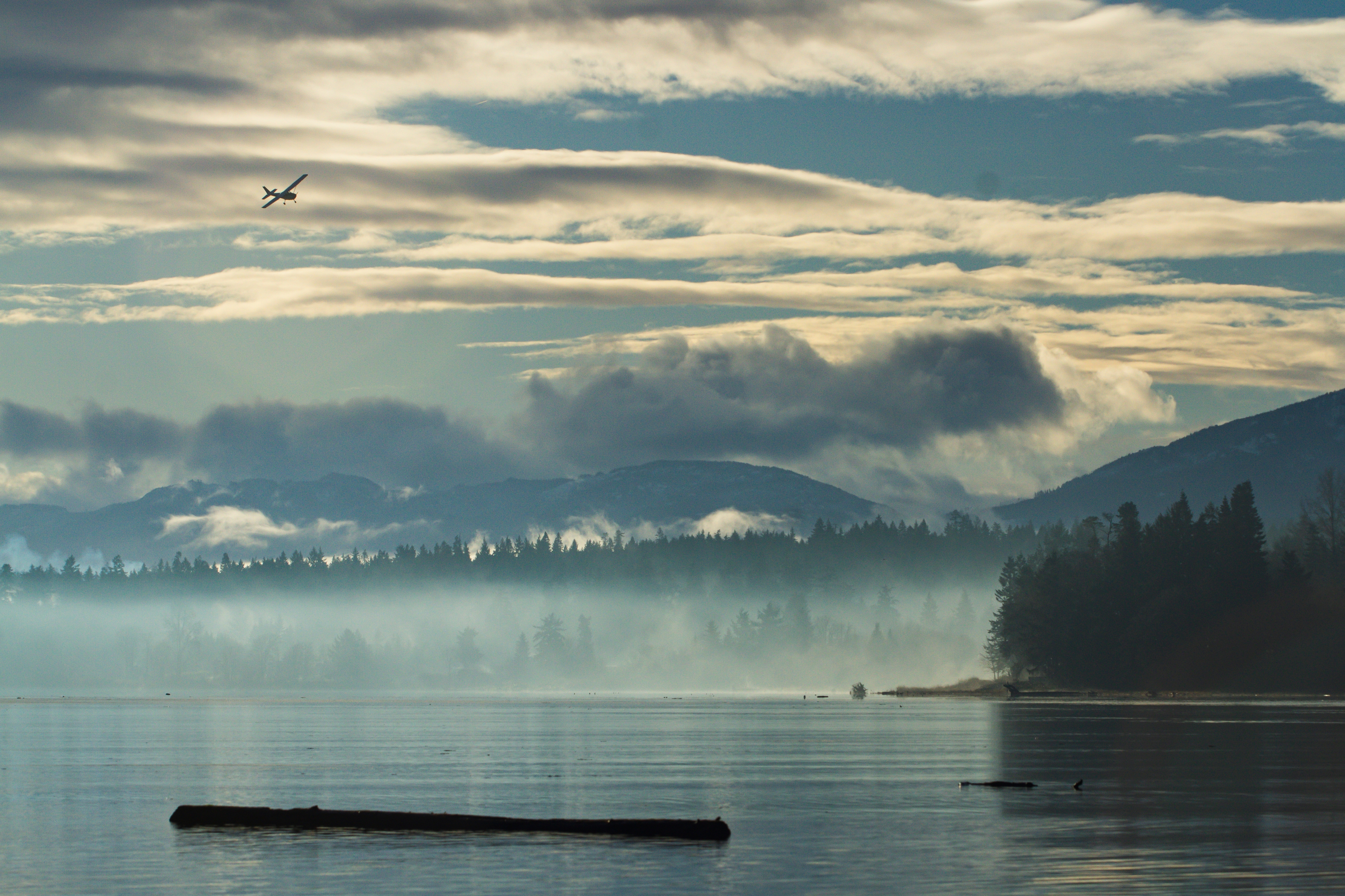 A small single engine plane makes its way in for a landing among the mountains in Comox, BC.