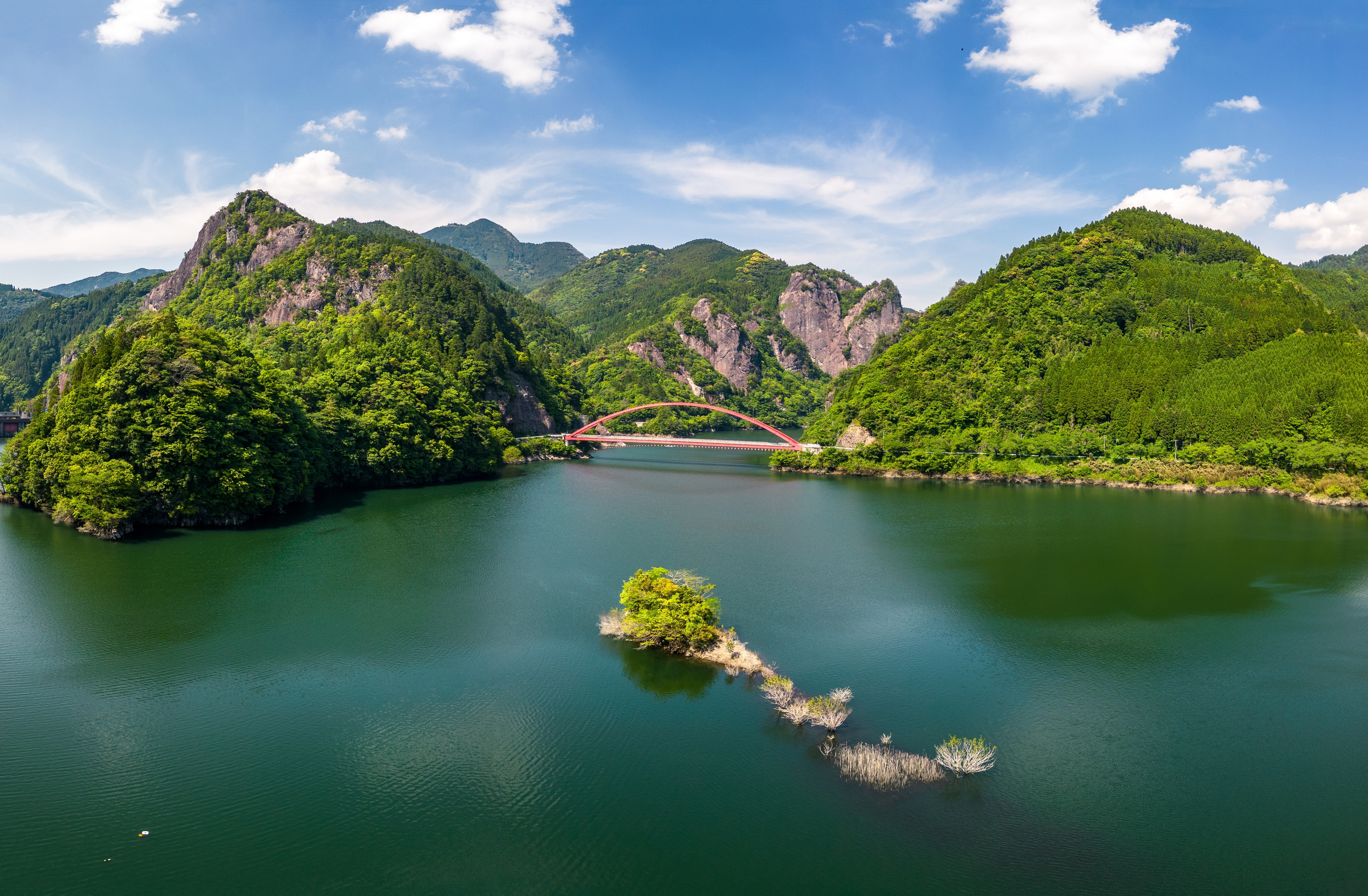 Kyushu, Japan: Dramatic aerial panorama of the Hyugami Dam reservoir and gorge with a red bridge in the mountain of Kyushu island in Japan in springtime.