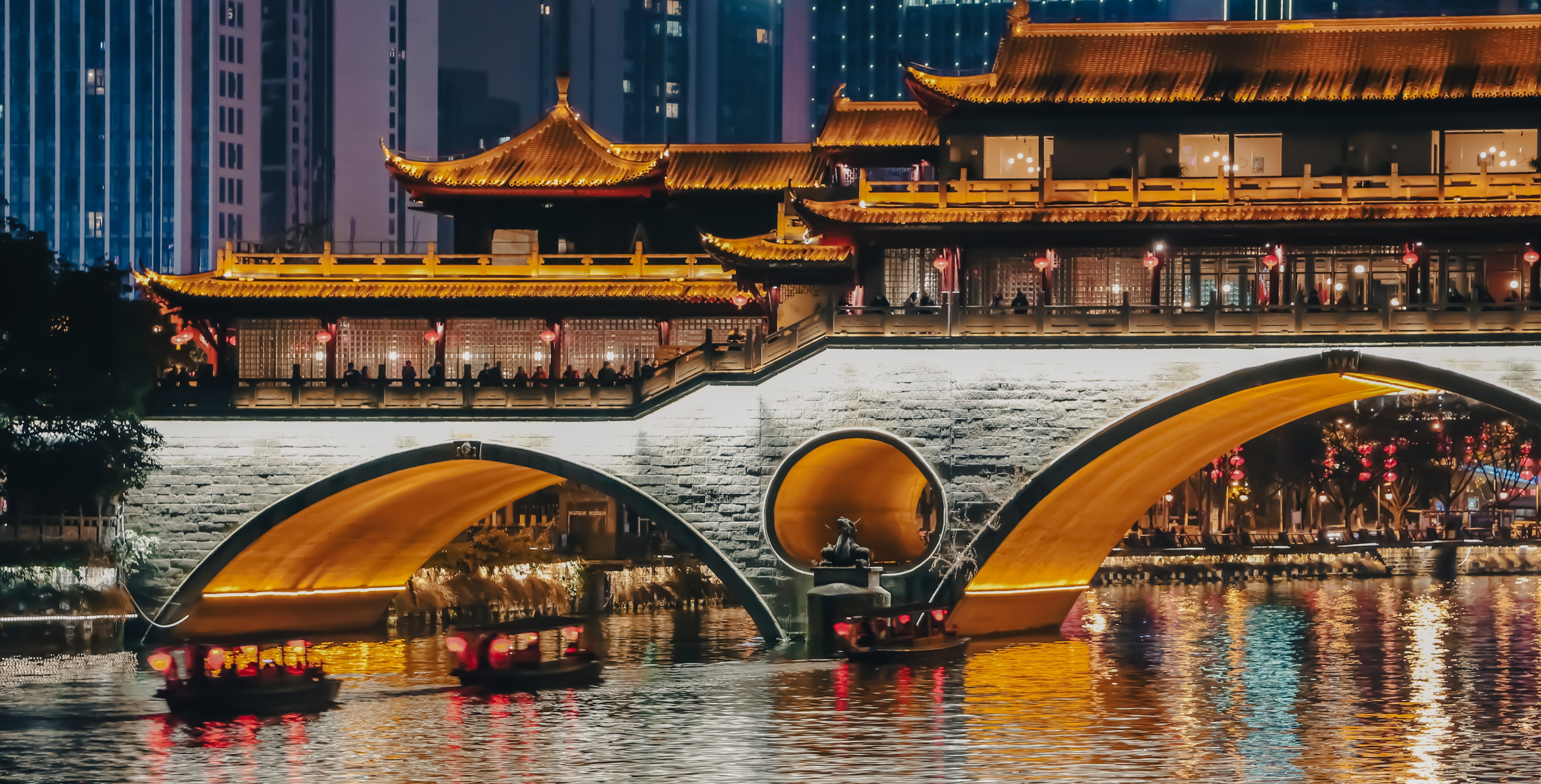 Three little tour boats with red lanterns, cross the famous Anshun Bridge on the Jinjiang River of Chengdu, Sichuan, China