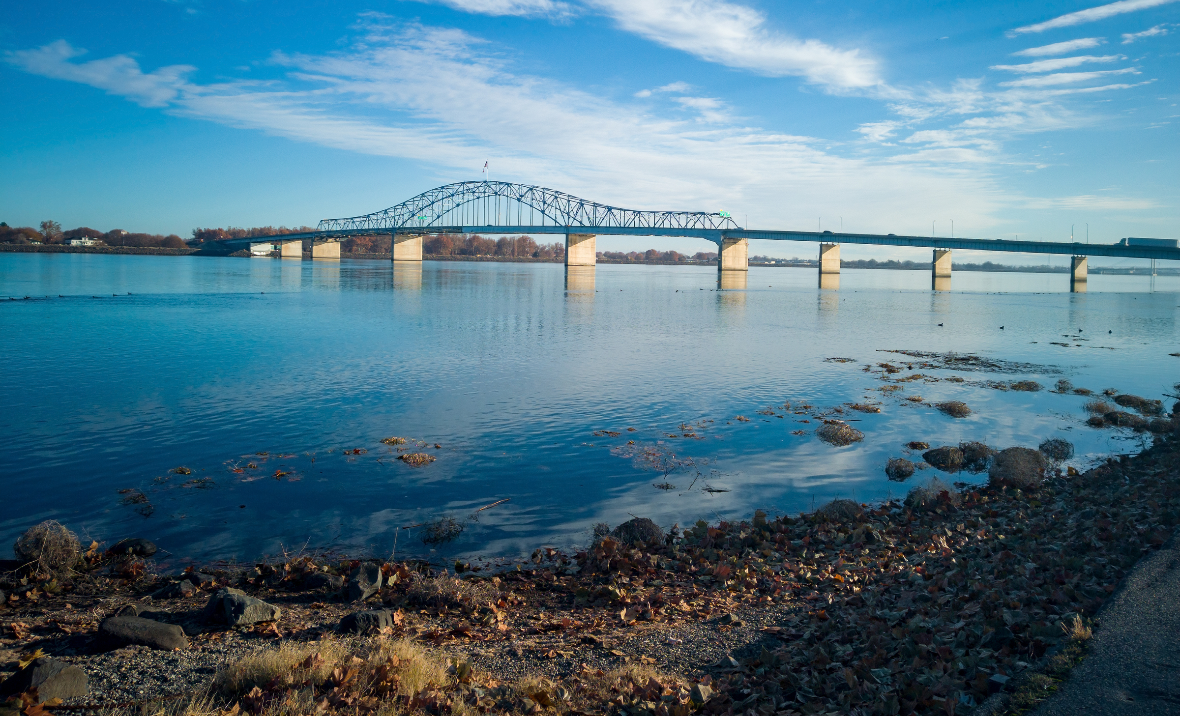 Historic blue and white arch truss bridge over the Columbia River with blue skies and clouds on a sunny morning in Kennewick-Pasco Washington