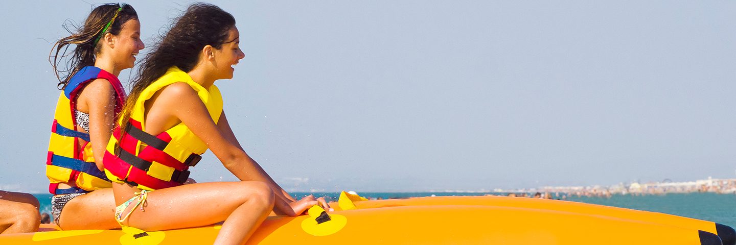 extreme speed attraction in the sea.ea attraction. Group of young enjoying a ride on a banana boat on sunny summer day. Beach water sport