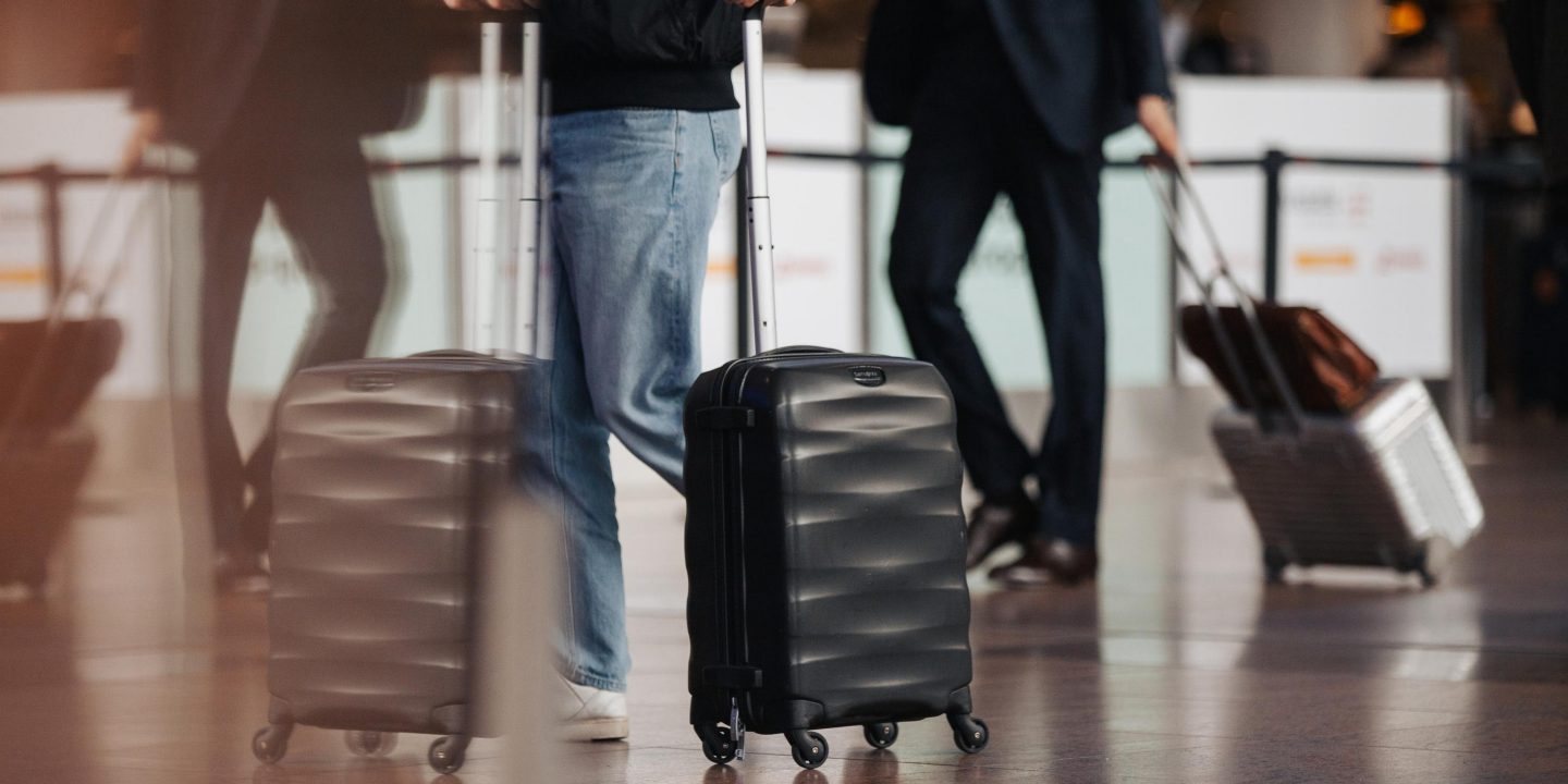 Des personnes marchant avec des valises à roulettes dans un terminal d’aéroport.