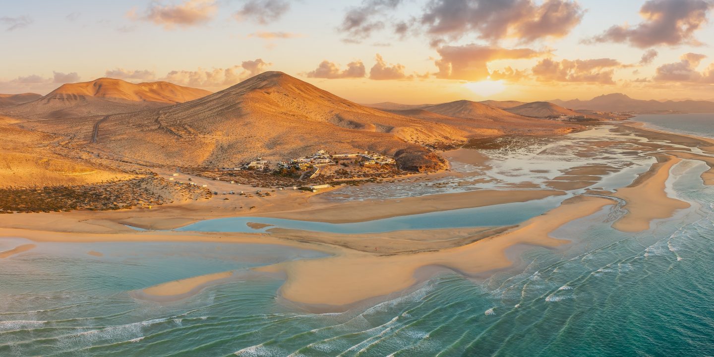 Playa de Sotavento at sunrise, Fuerteventura: a breathtaking aerial view of crystal-clear lagoons and sweeping sand dunes on this iconic Canary beach.