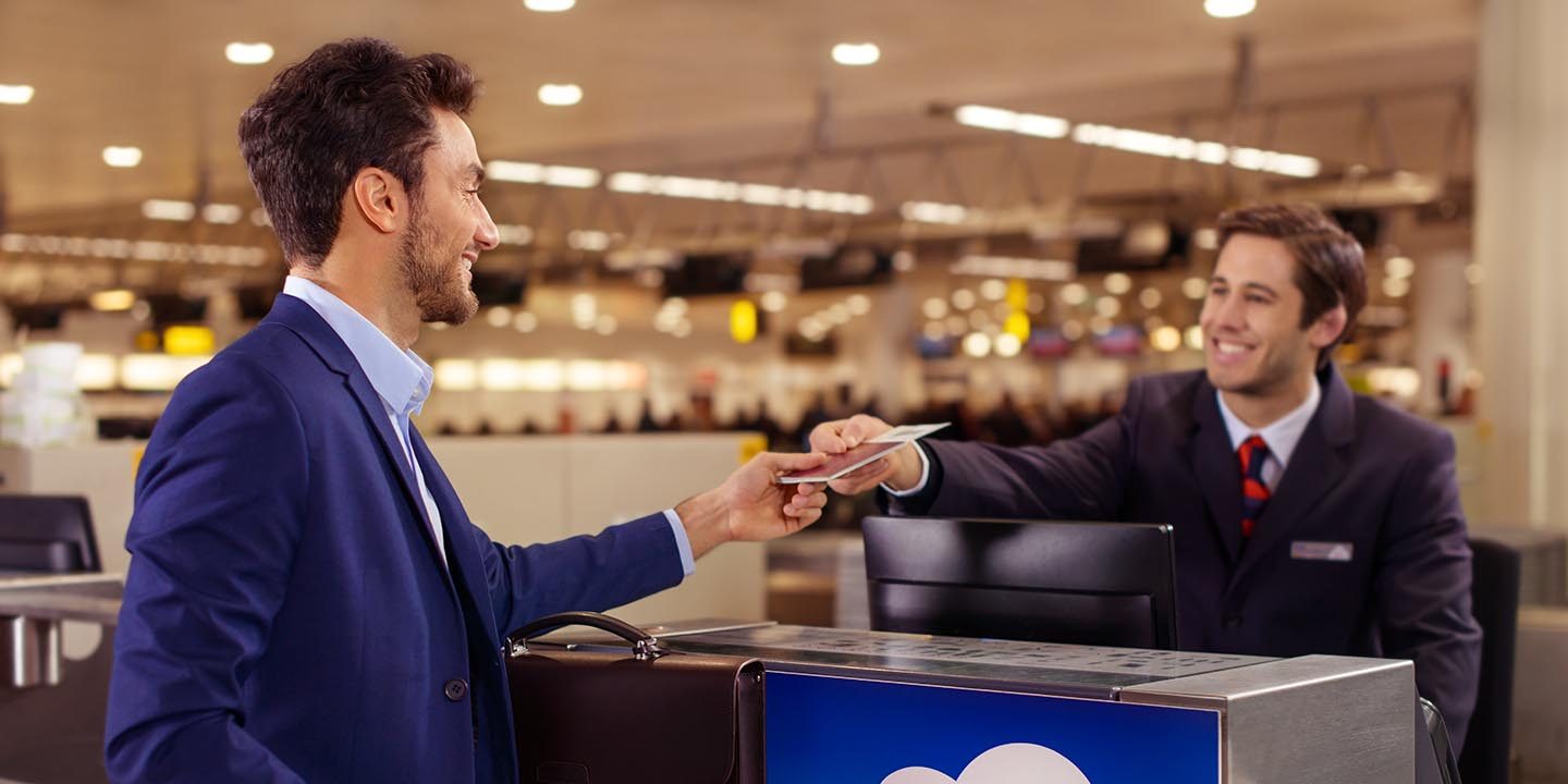 Ground staff handing documents to passenger at check-in