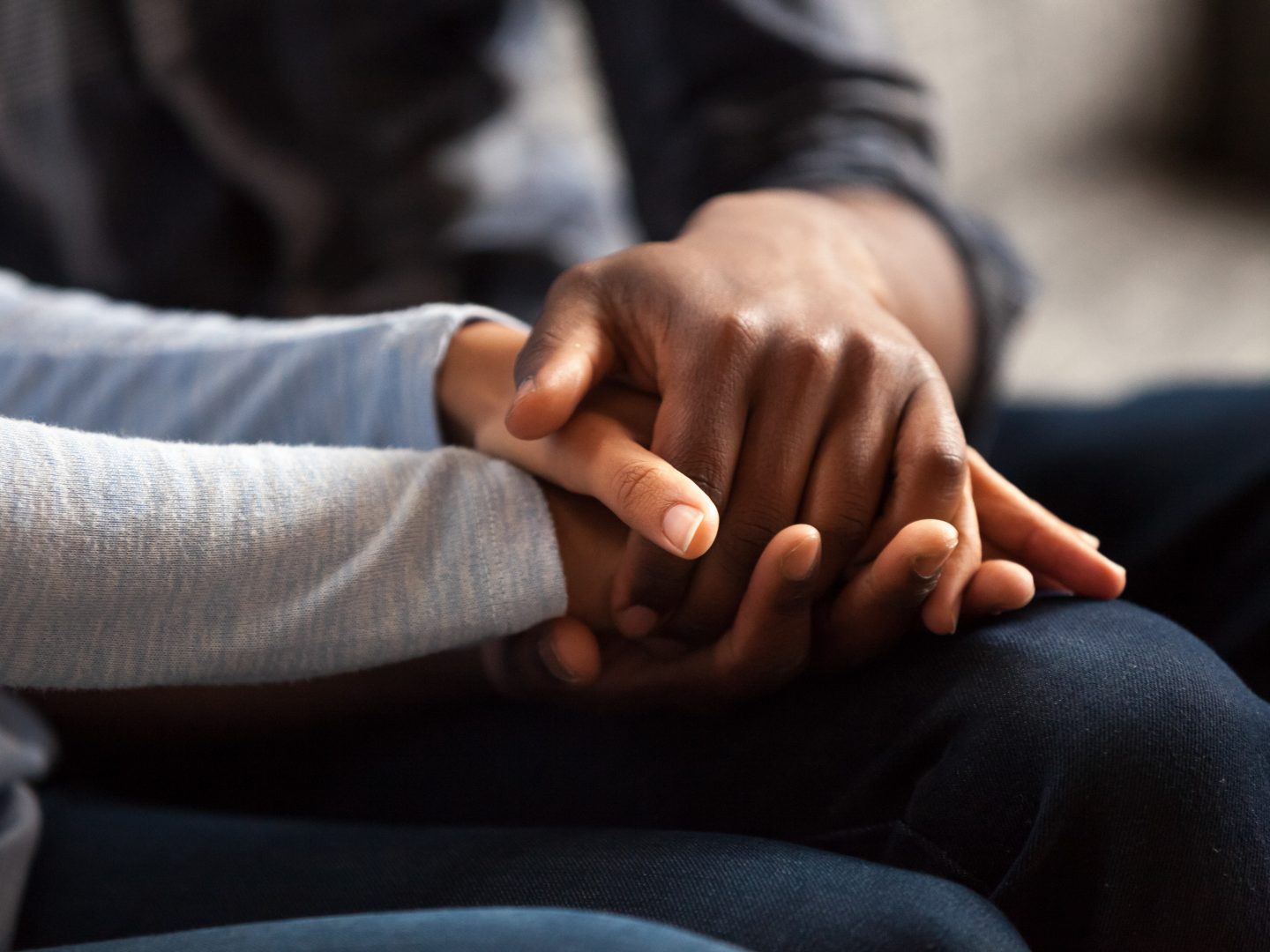 Close up black woman and man in love sitting on couch two people holding hands. Symbol sign sincere feelings, compassion, loved one, say sorry. Reliable person, trusted friend, true friendship concept